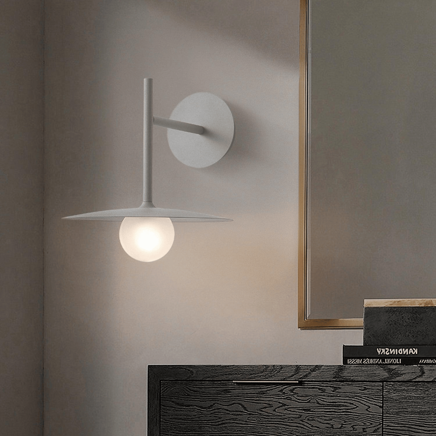 Modern wall lamp on a neutral wall with a mirror and wooden surface in the background