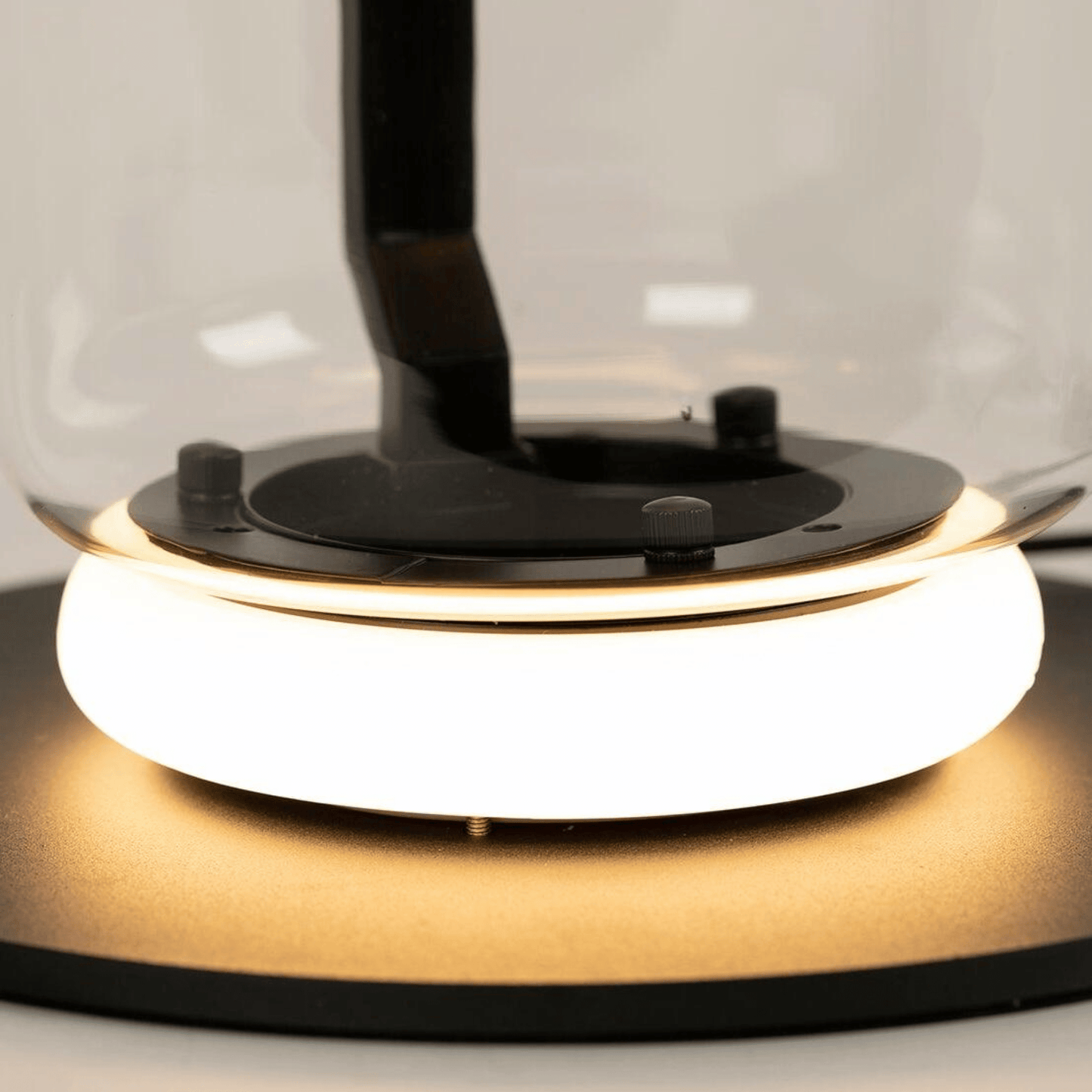 Close-up of a modern desk lamp with a glass shade and black base.