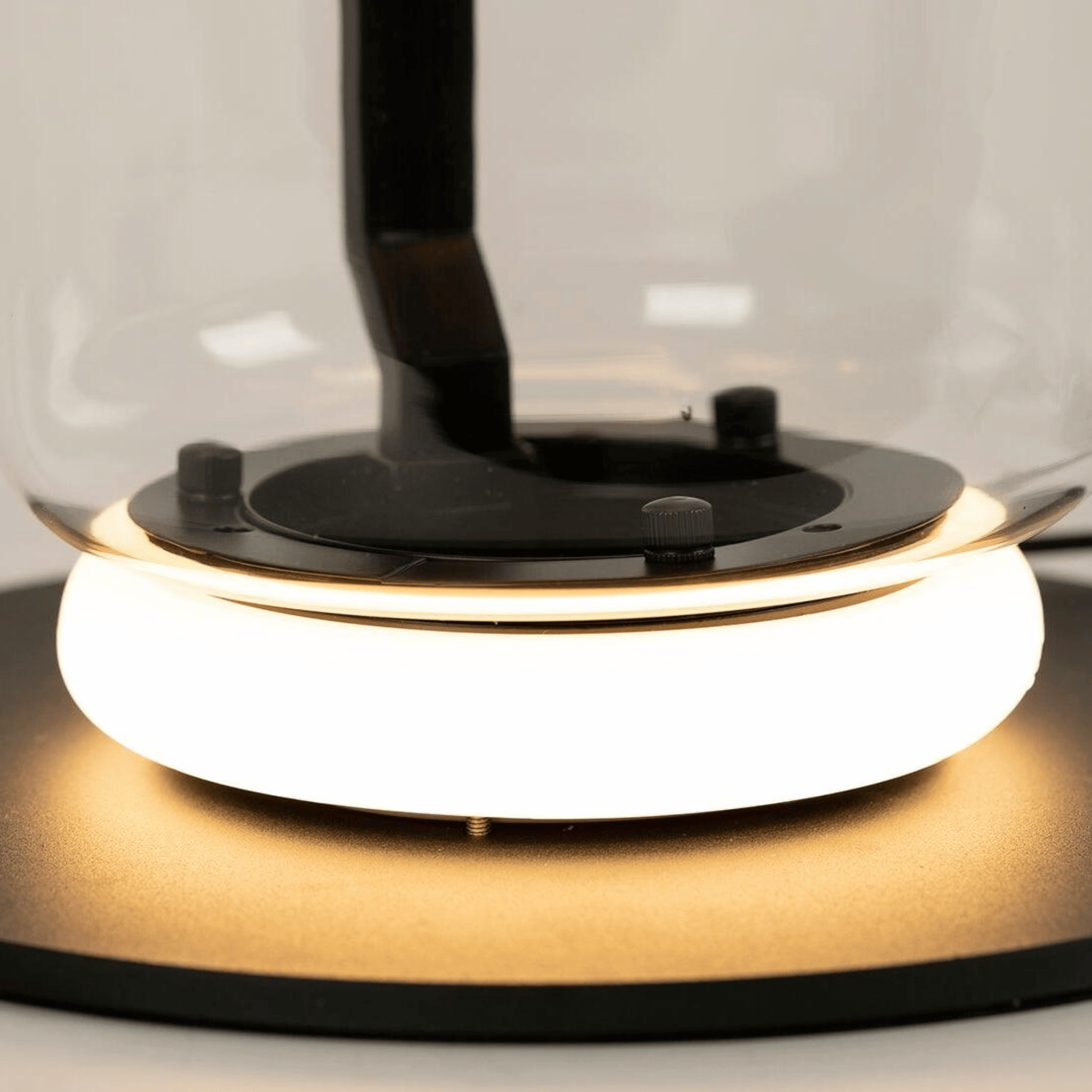 Close-up of a modern desk lamp with a glass shade and black base.