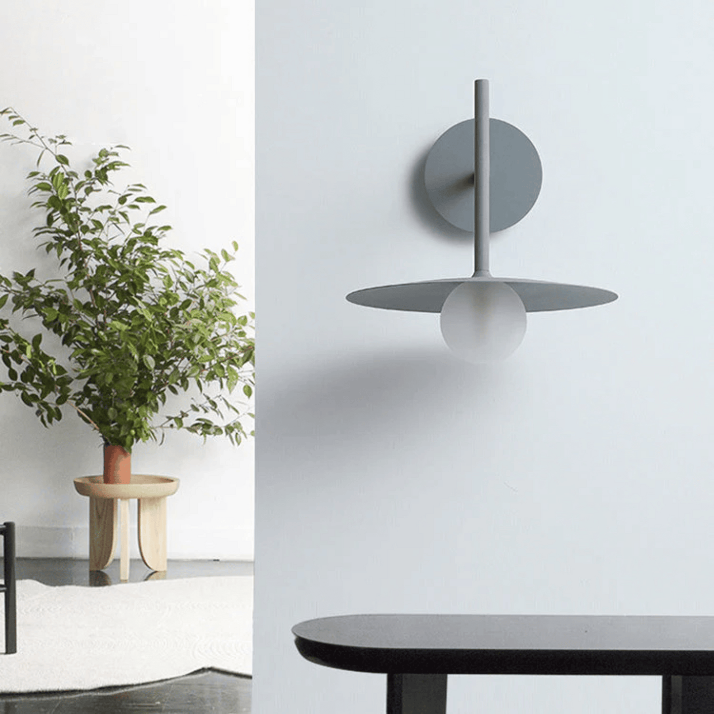 Modern wall sconce with a plant and table in a minimalistic room.