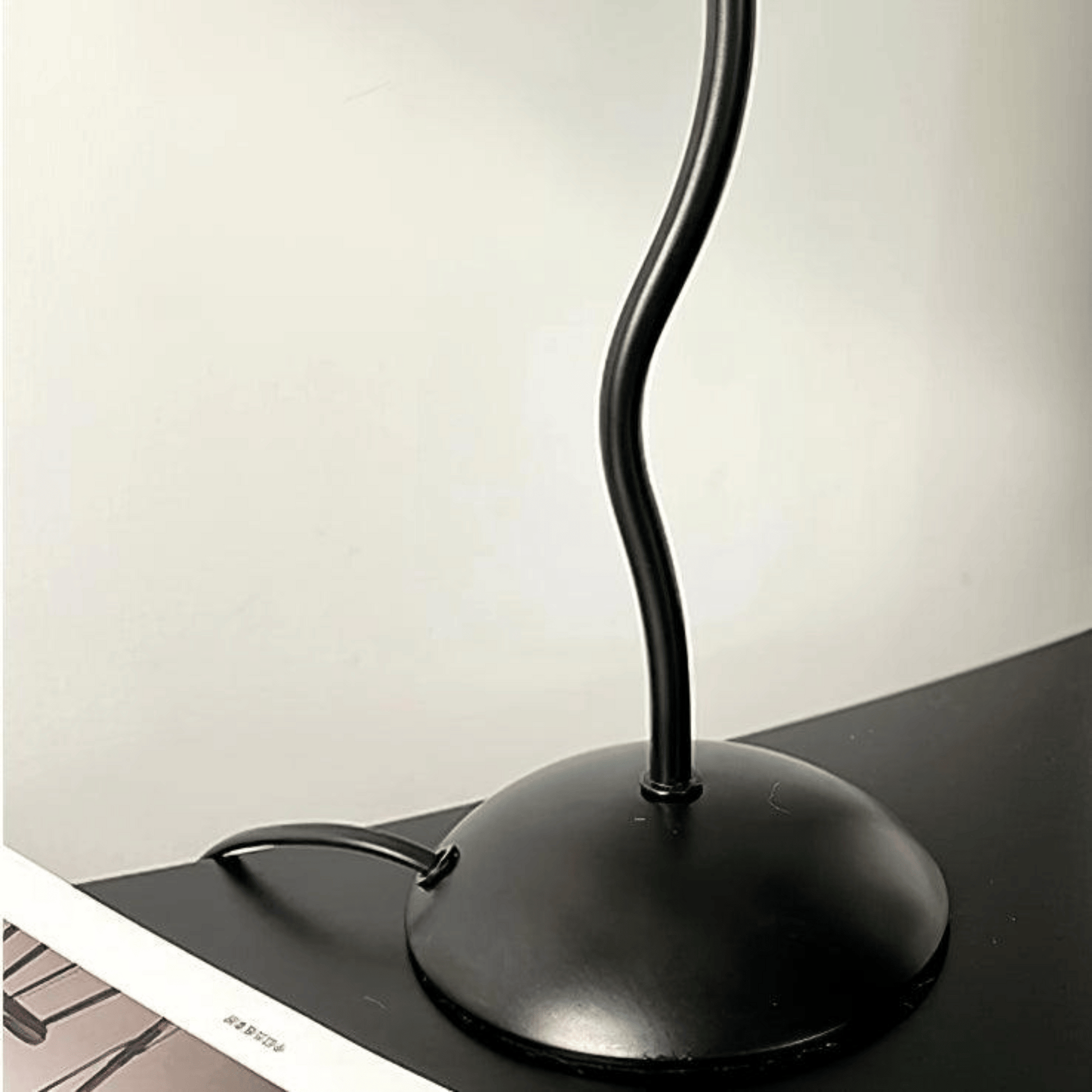 Black desk lamp on a desk with a neutral background