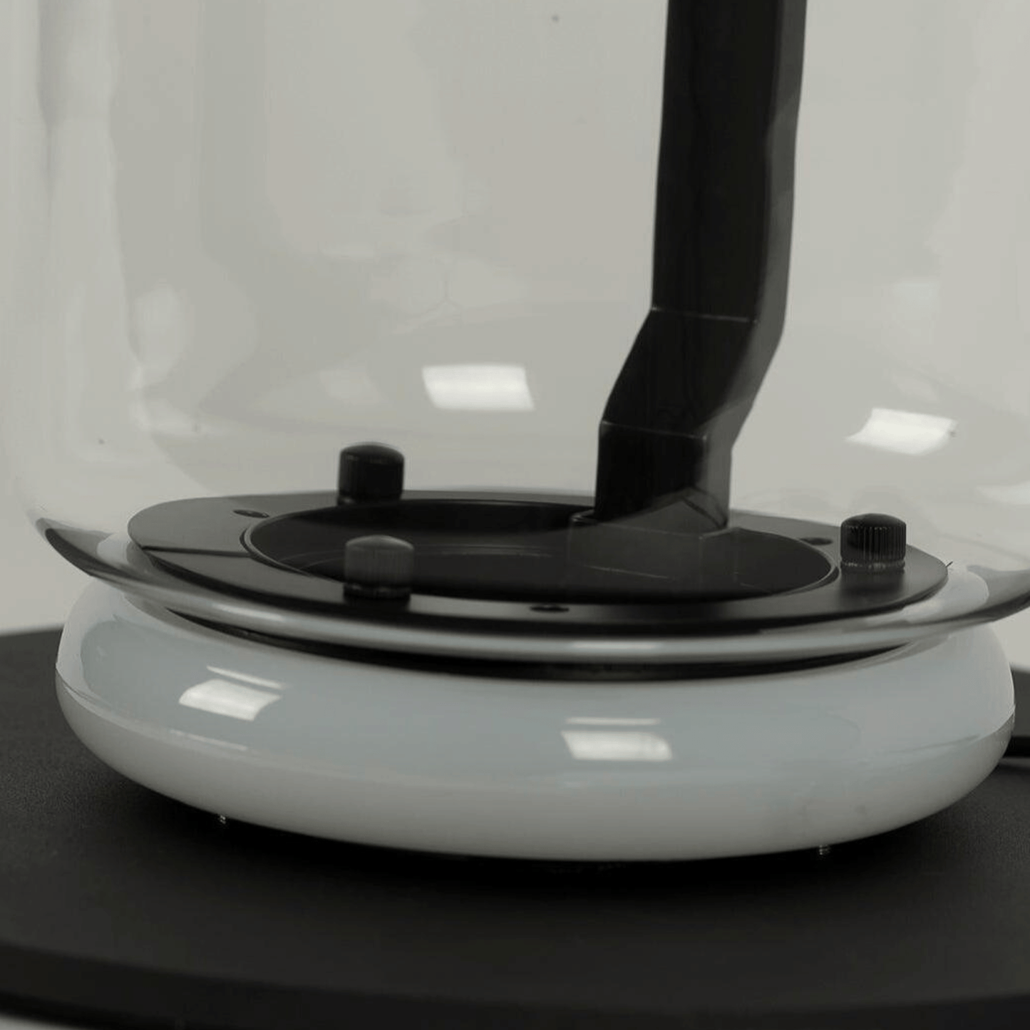 Close-up of a white and black electronic device on a reflective surface with a blurred background