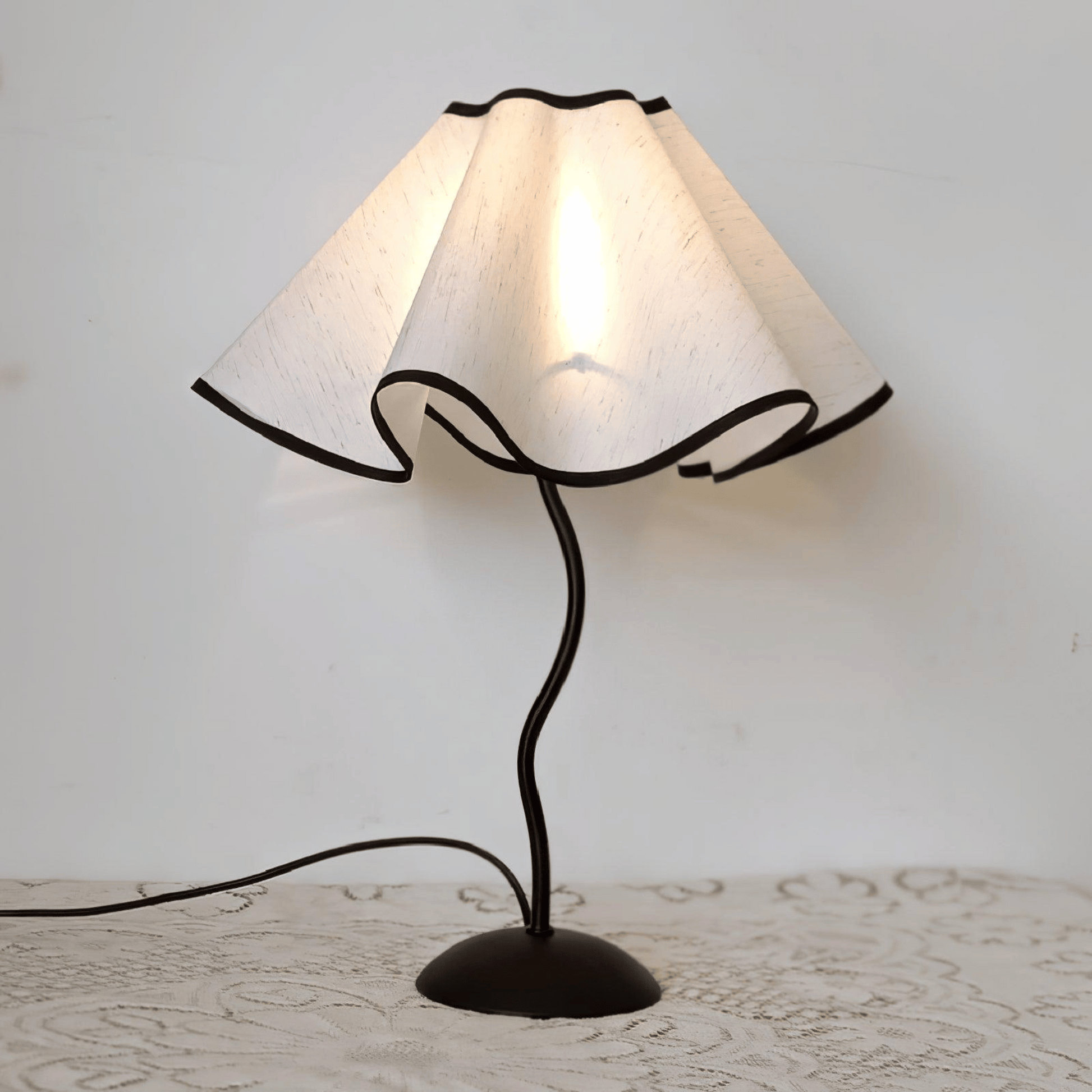 Table lamp with white lampshade and black base on a textured surface.