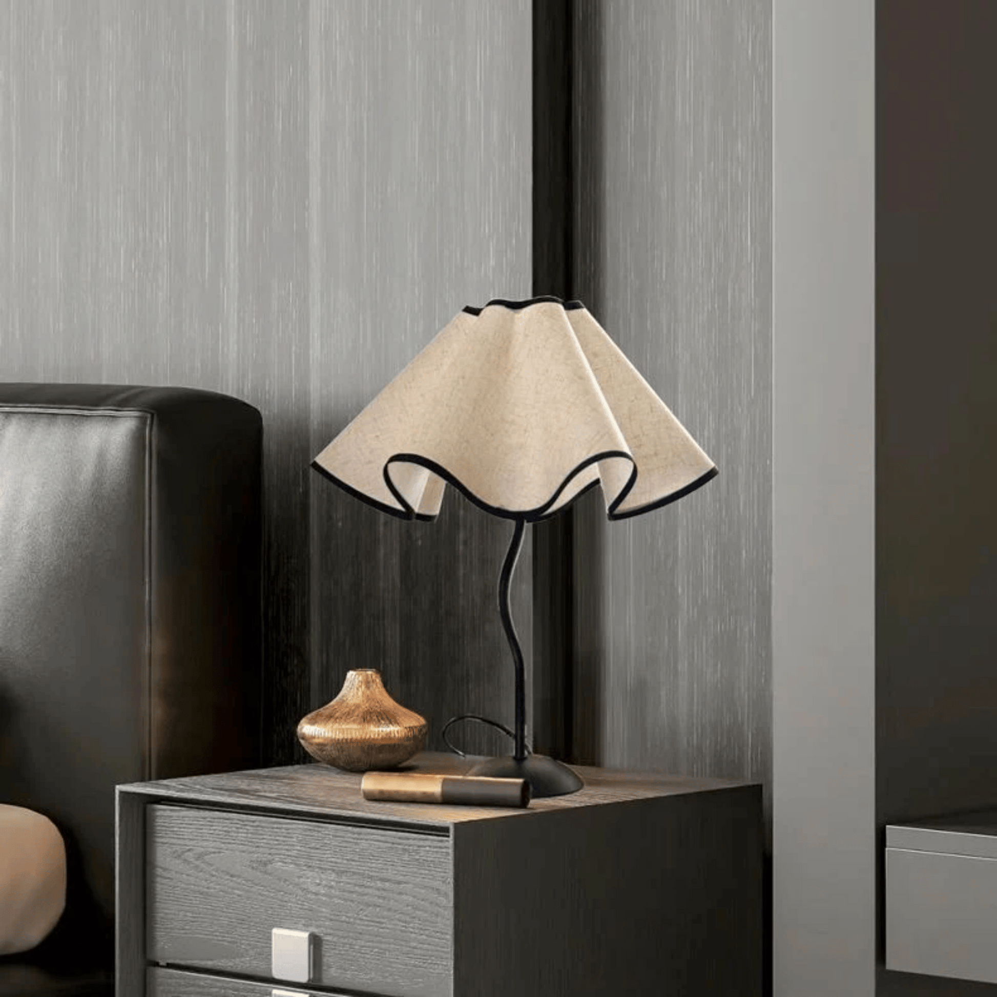 Table lamp with beige shade on a wooden nightstand against a gray wall.