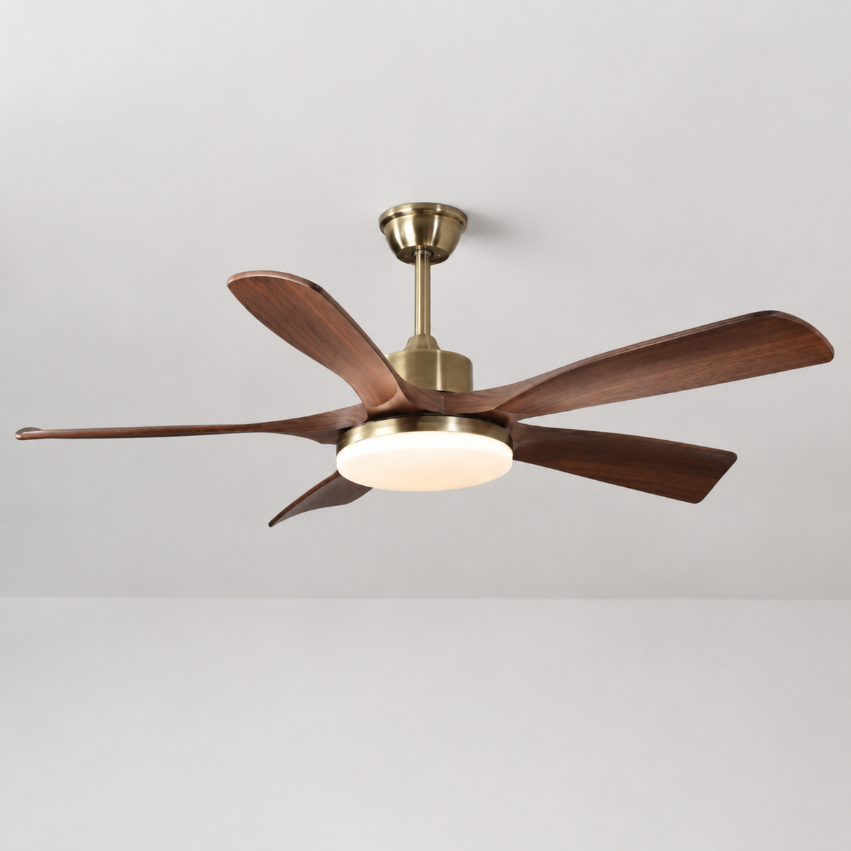 Ceiling fan with wooden blades and brass finish on a plain background
