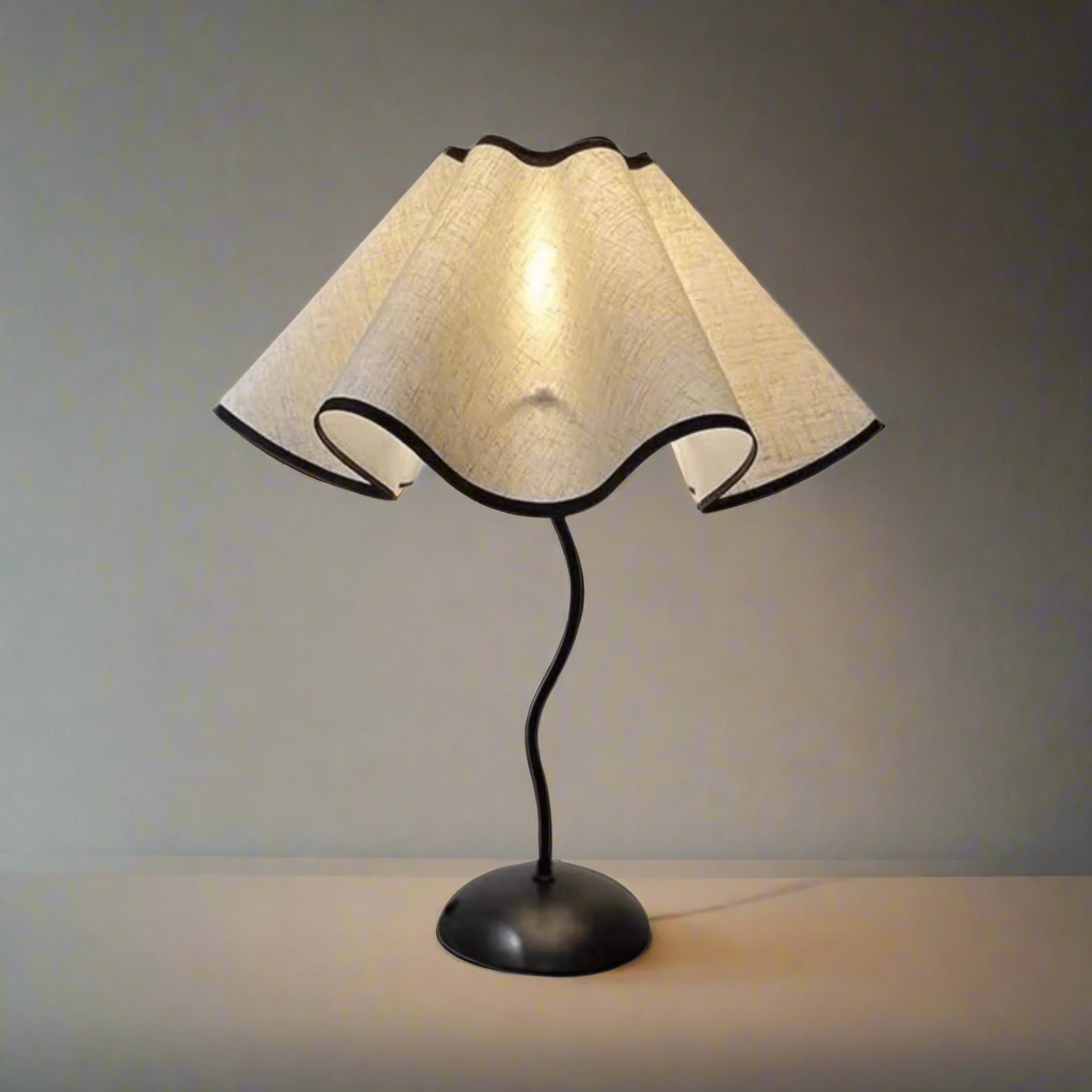 Table lamp with beige fabric shade and black metal base on a white background