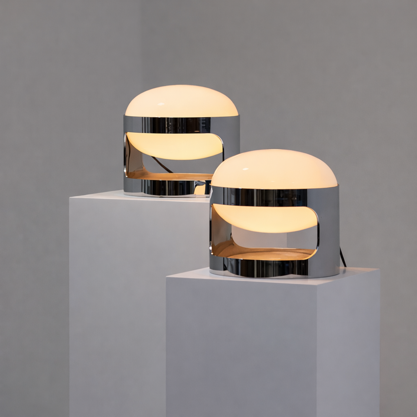 Two modern table lamps on gray pedestals against a gray background