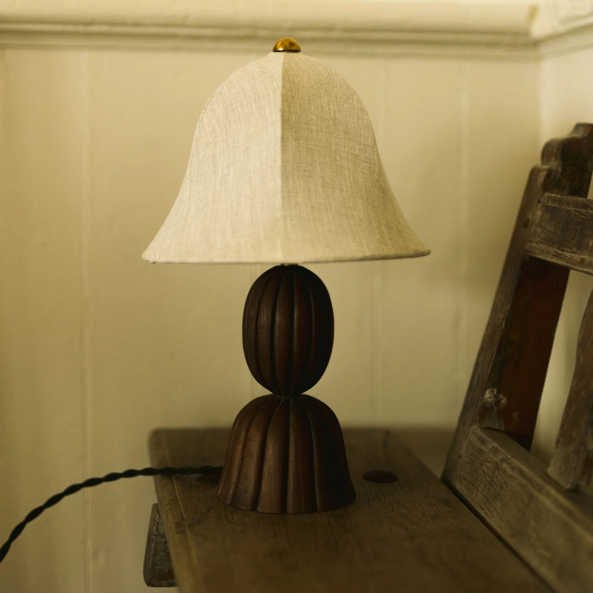 Table lamp with wooden base and beige fabric shade on a wooden surface.