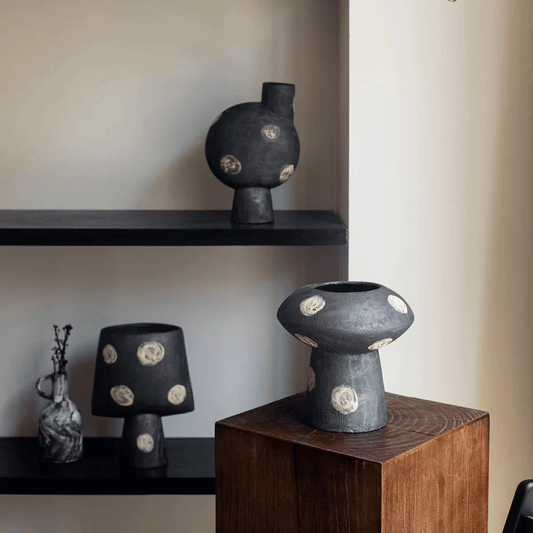 Black ceramic vases with gold accents on a wooden pedestal and shelves.