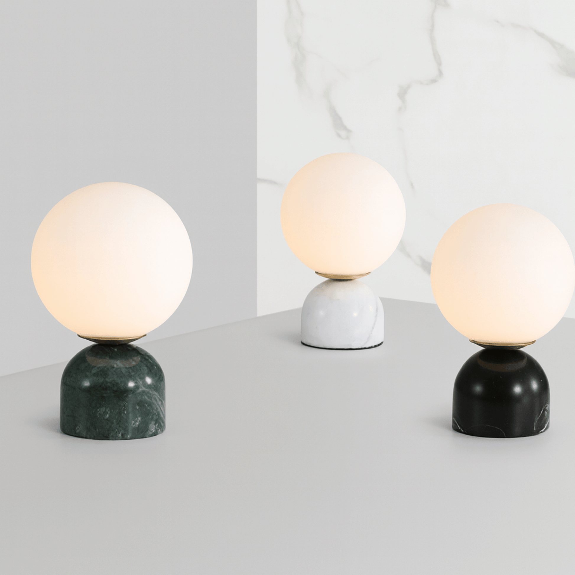 Three table lamps with marble bases on a light gray surface.