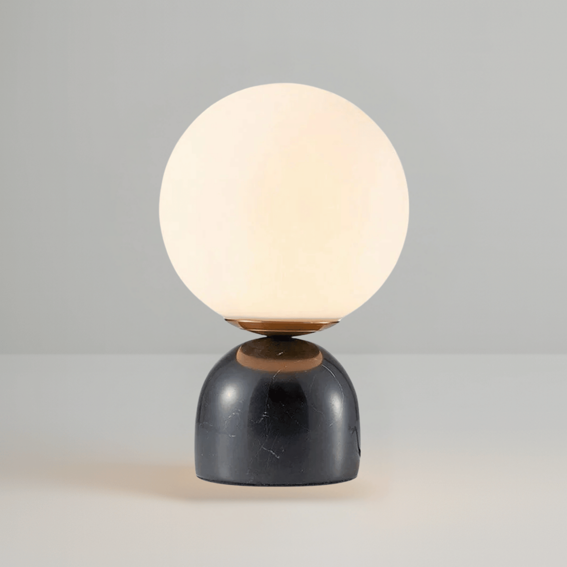 Table lamp with a round white glass shade and black base on a gray background