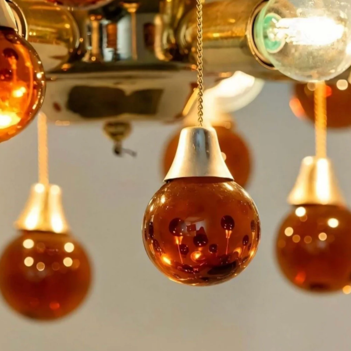 Close-up of a chandelier with orange glass bulbs and metallic fixtures.