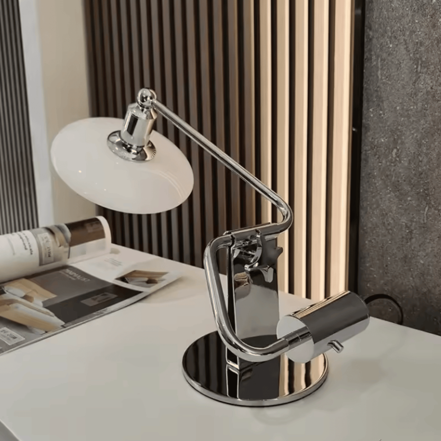 Modern desk lamp on a white surface with a magazine in the background