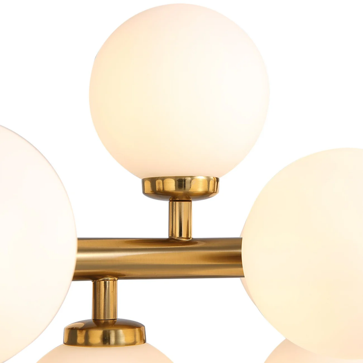 Close-up of a gold fixture with three round glass shades on a white background