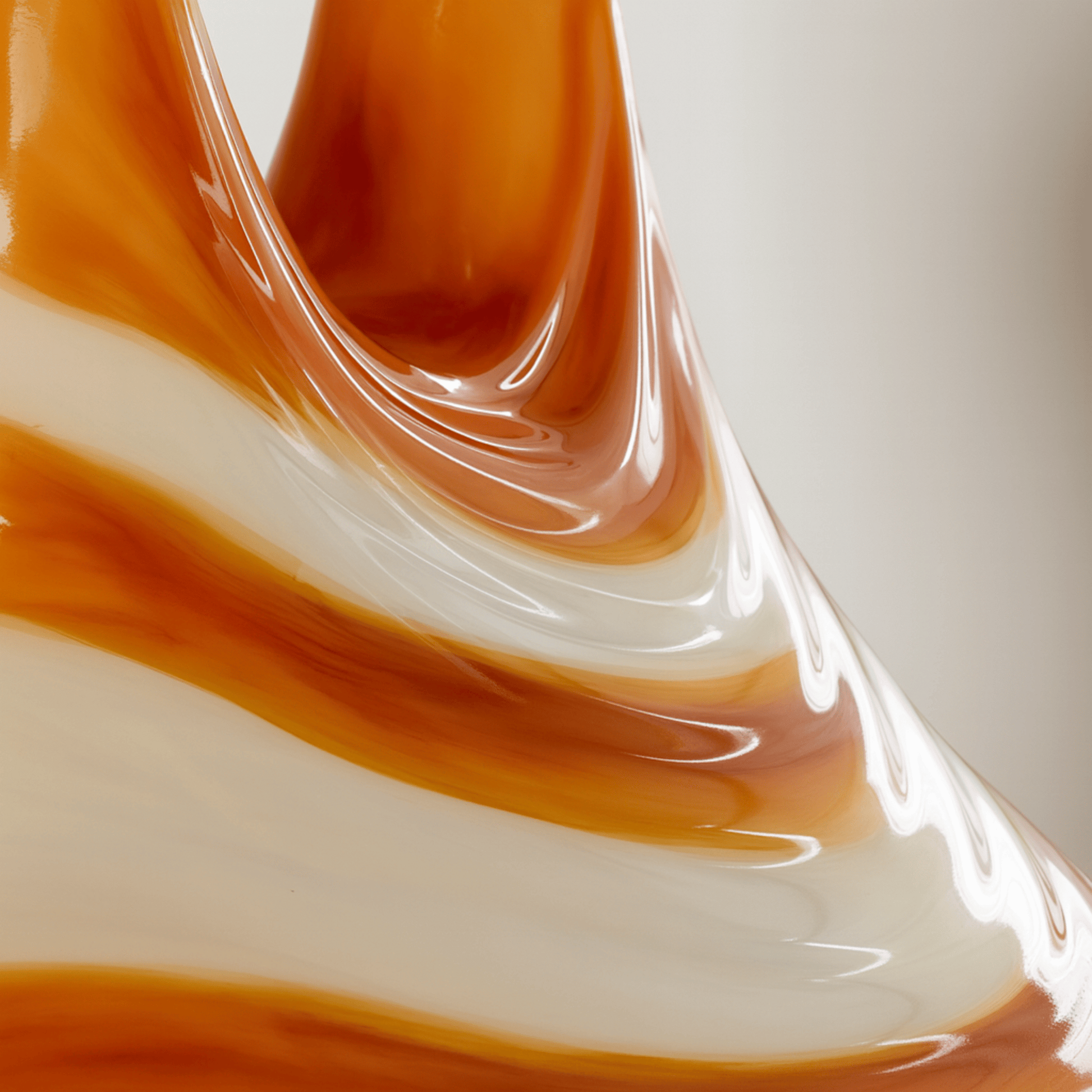 Close-up of a glass object with orange and white swirls on a light background