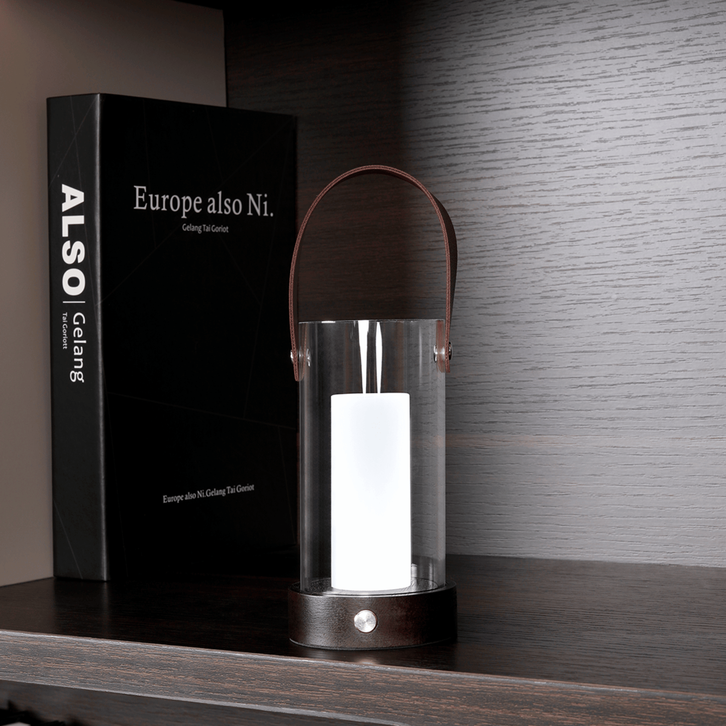 Glass lantern with wooden handle on a shelf next to a black box labeled 'ALSO Gelang'.