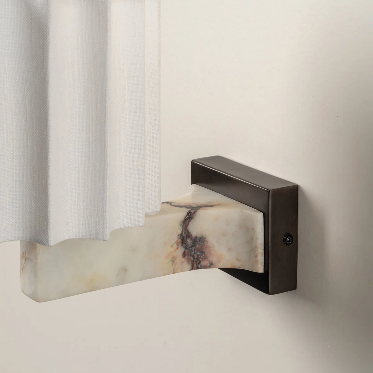 Decorative wall sconce with marble base and bronze finish on a neutral background