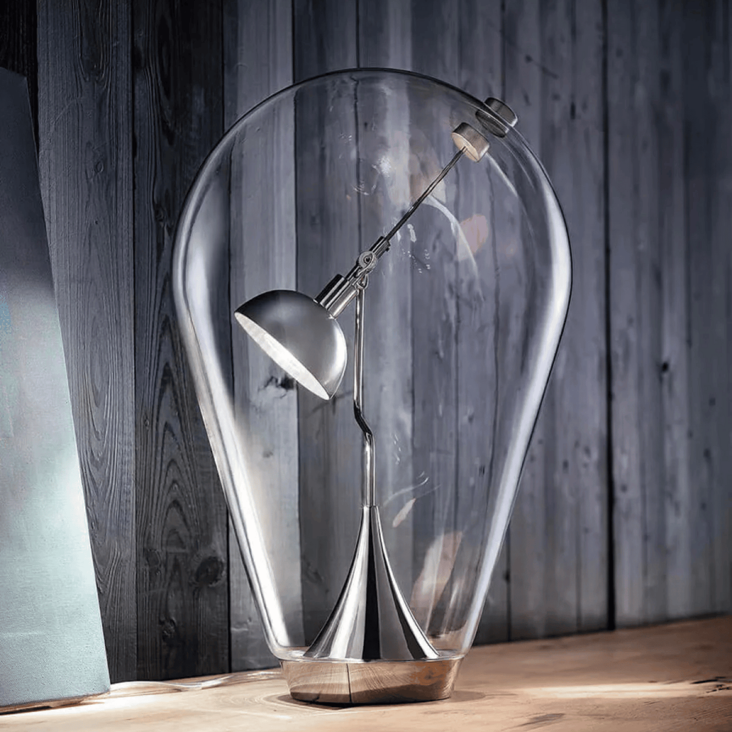 Modern table lamp with a clear glass shade on a wooden surface.