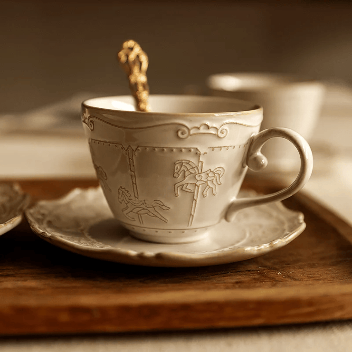 Decorative ceramic cup and saucer with intricate designs on a wooden surface.