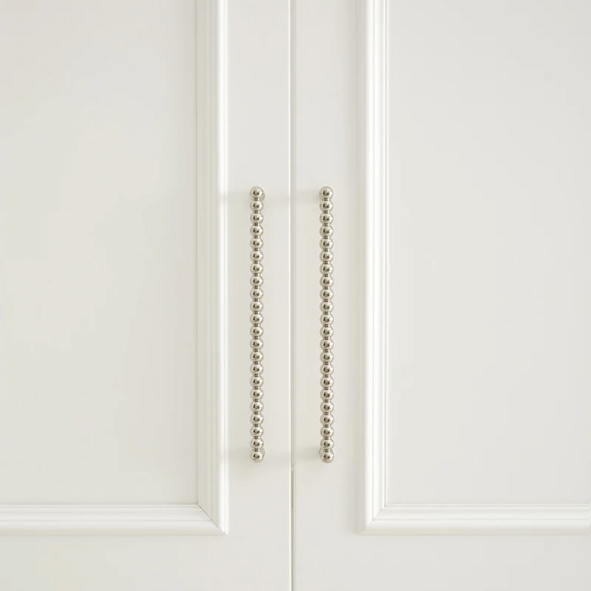 Close-up of a white cabinet door with decorative metal handle