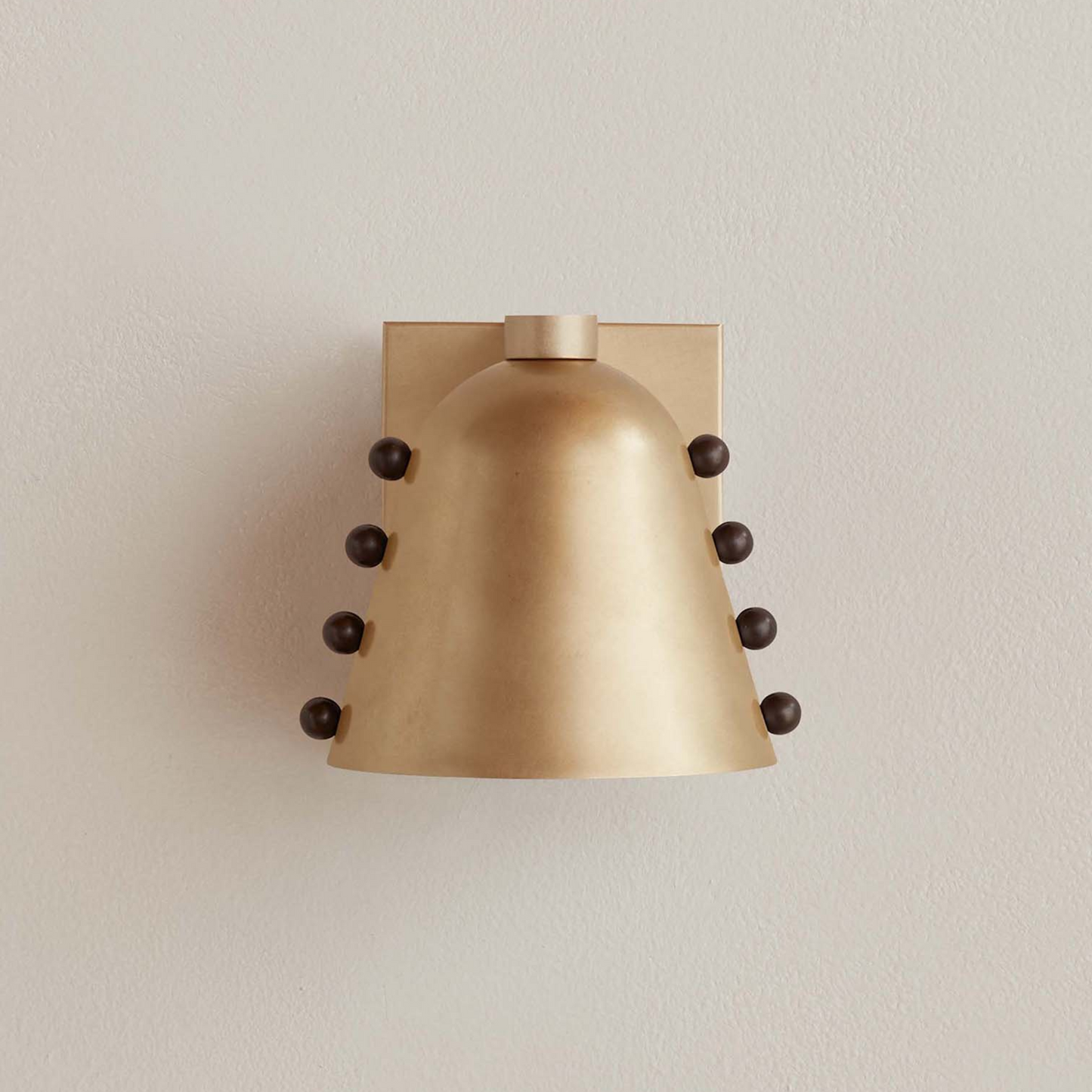 Brass wall sconce with black accents on a beige wall