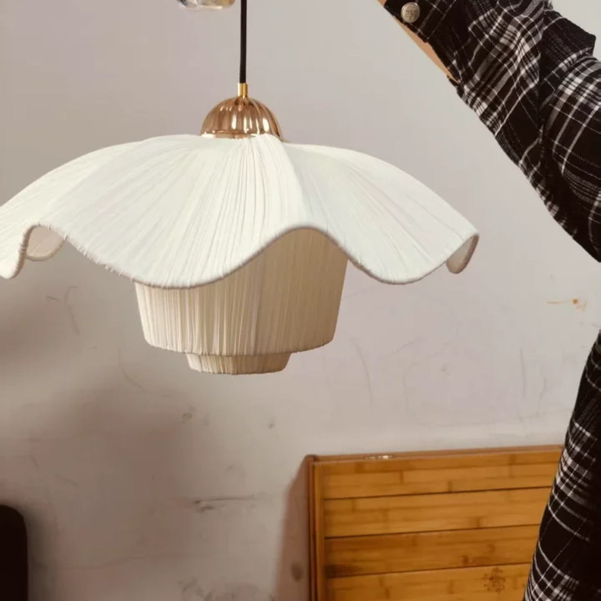Floral-patterned pendant light with gold fixture against a neutral wall.