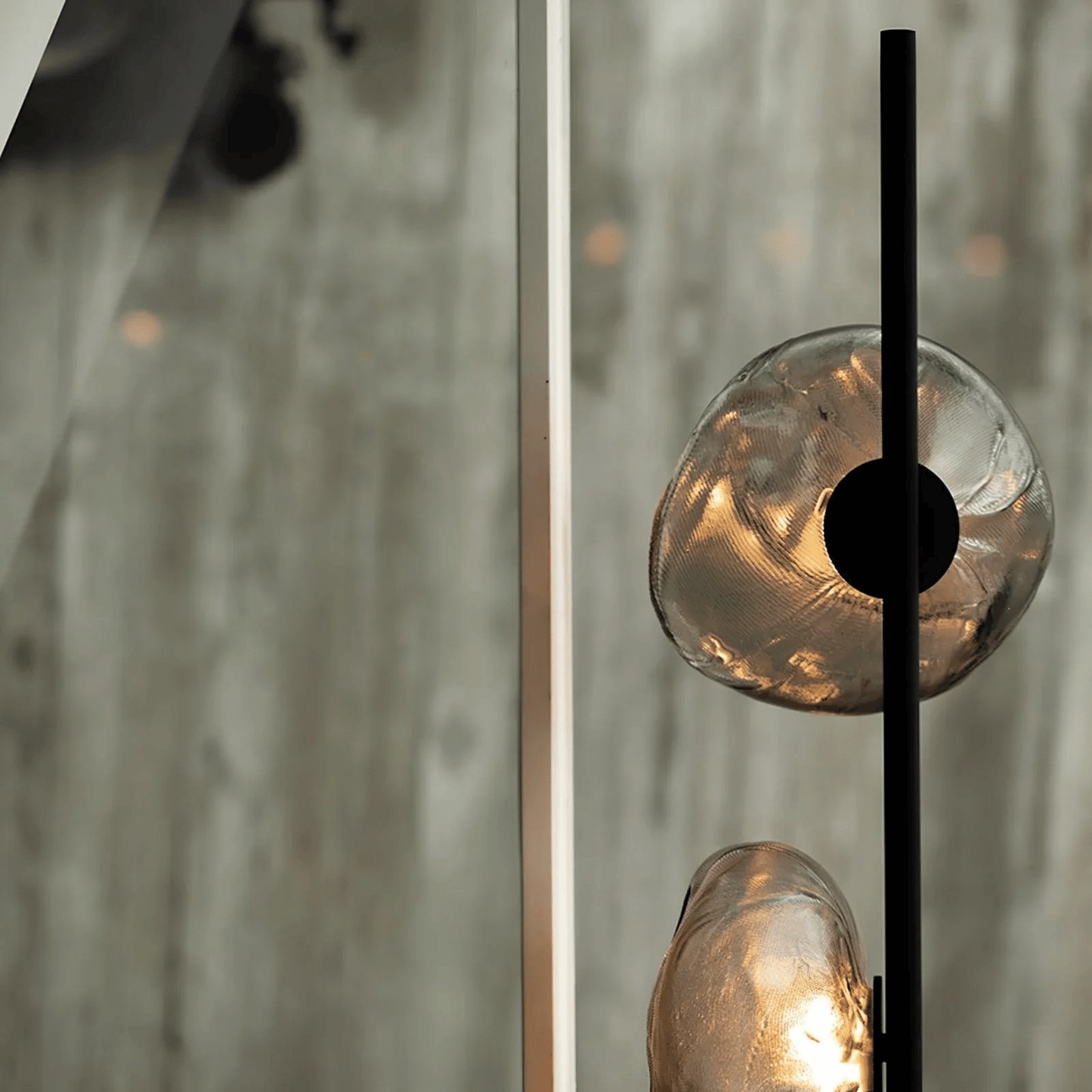 Close-up of a modern light fixture with glass shades and a black metal arm.