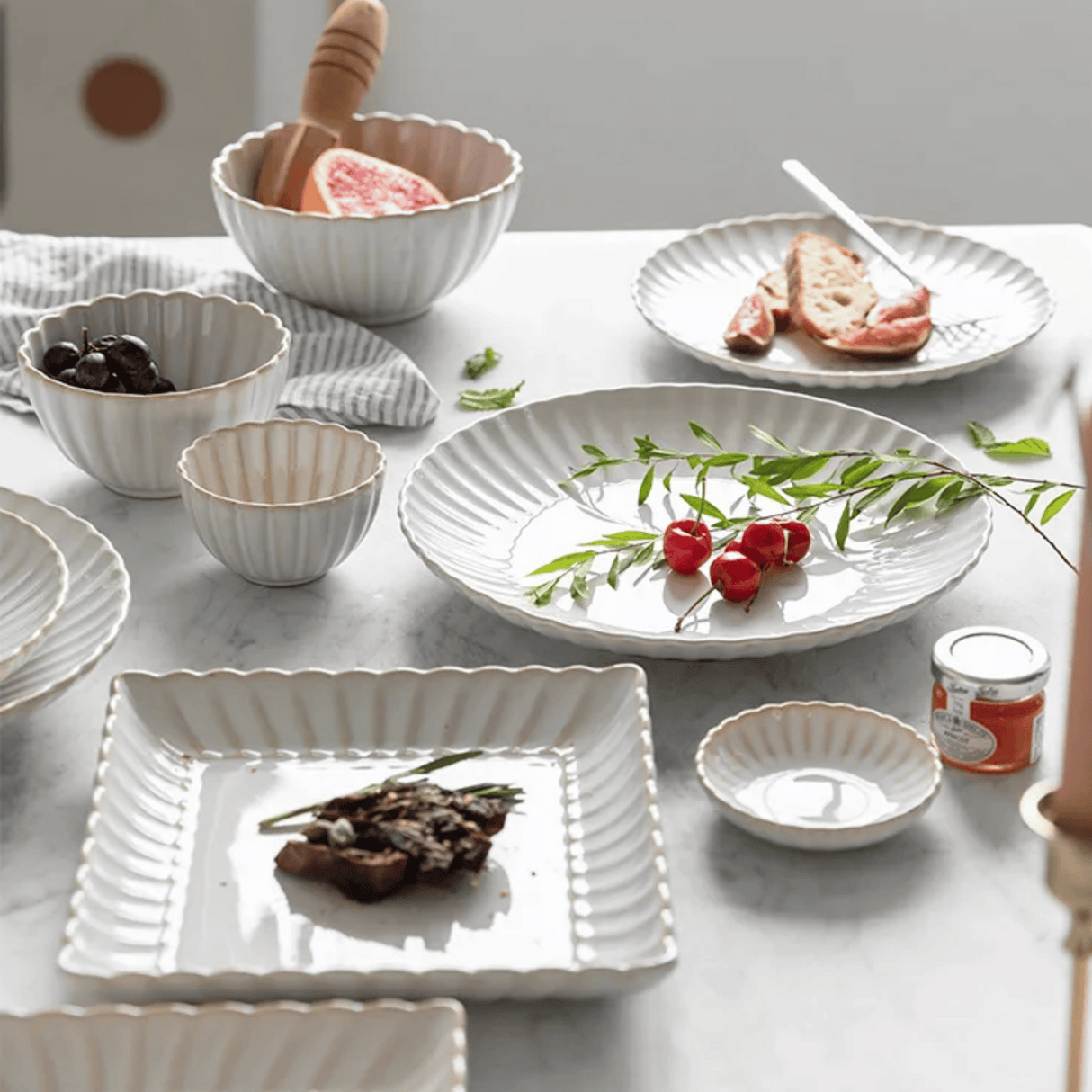 Set of white ceramic dishes on a table with food and garnishes.