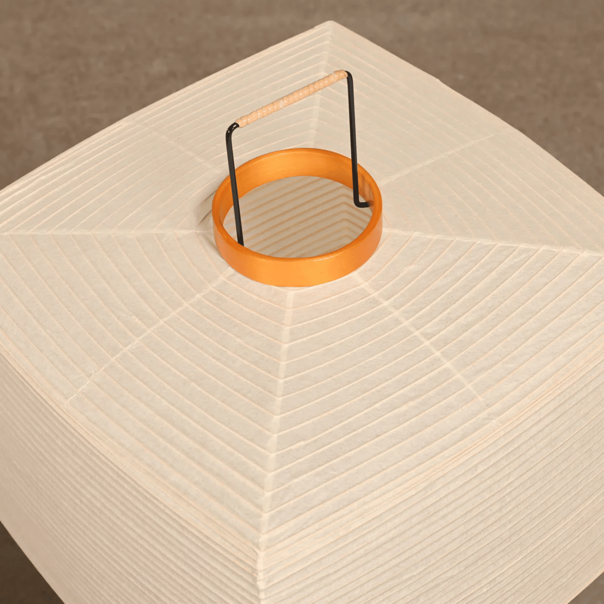 Orange ring with a black metal handle on a textured beige surface