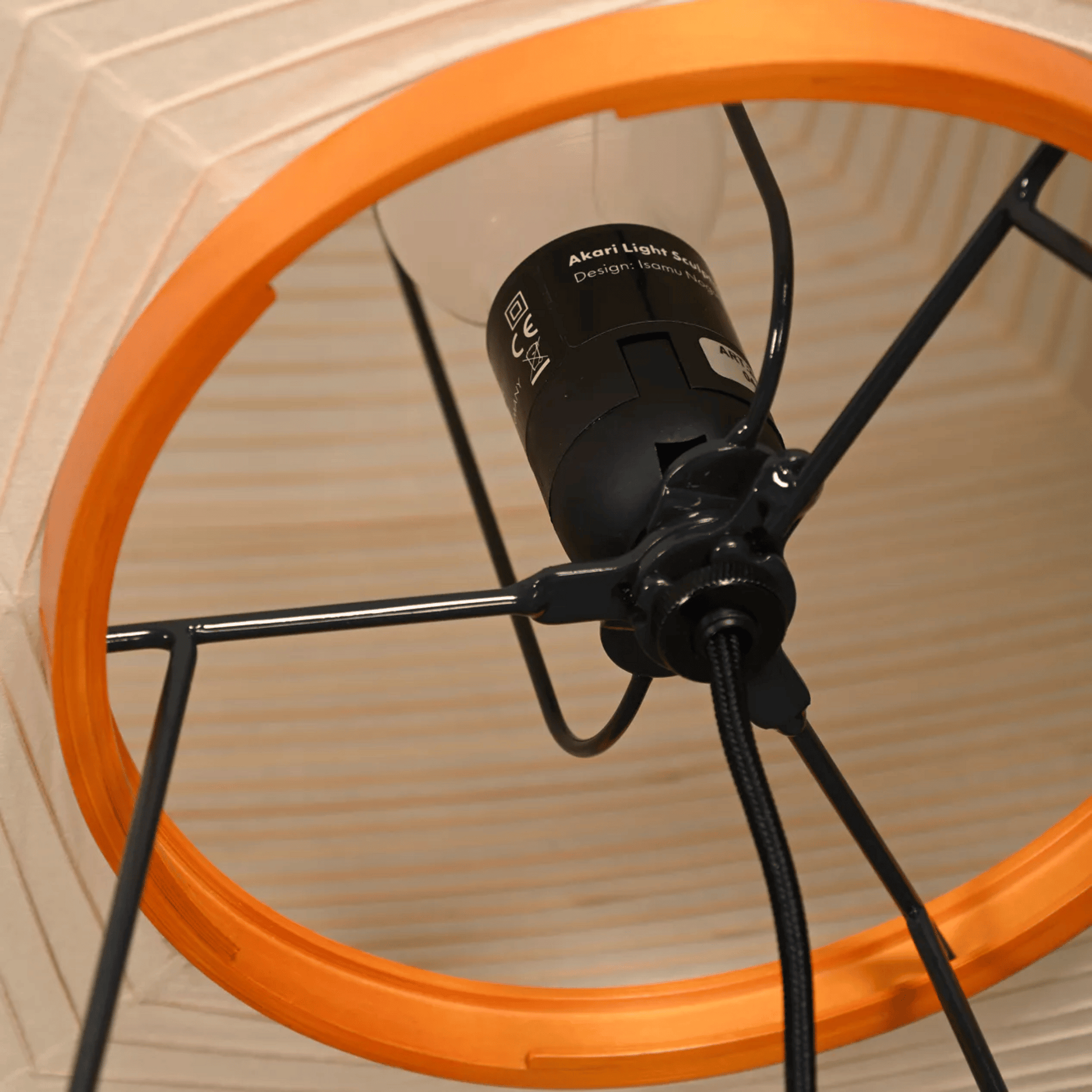 Close-up of a bicycle wheel with an orange rim and black hub on a wooden surface.
