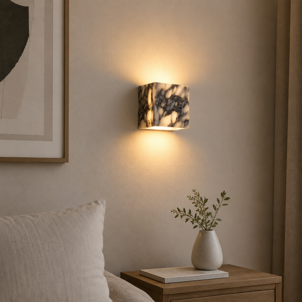 Wall-mounted lamp with marble pattern casting light on a neutral wall, with a vase and plant on a nightstand.