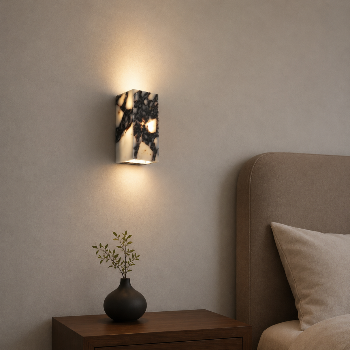 Wall sconce lighting a room with a vase and plant on a nightstand.