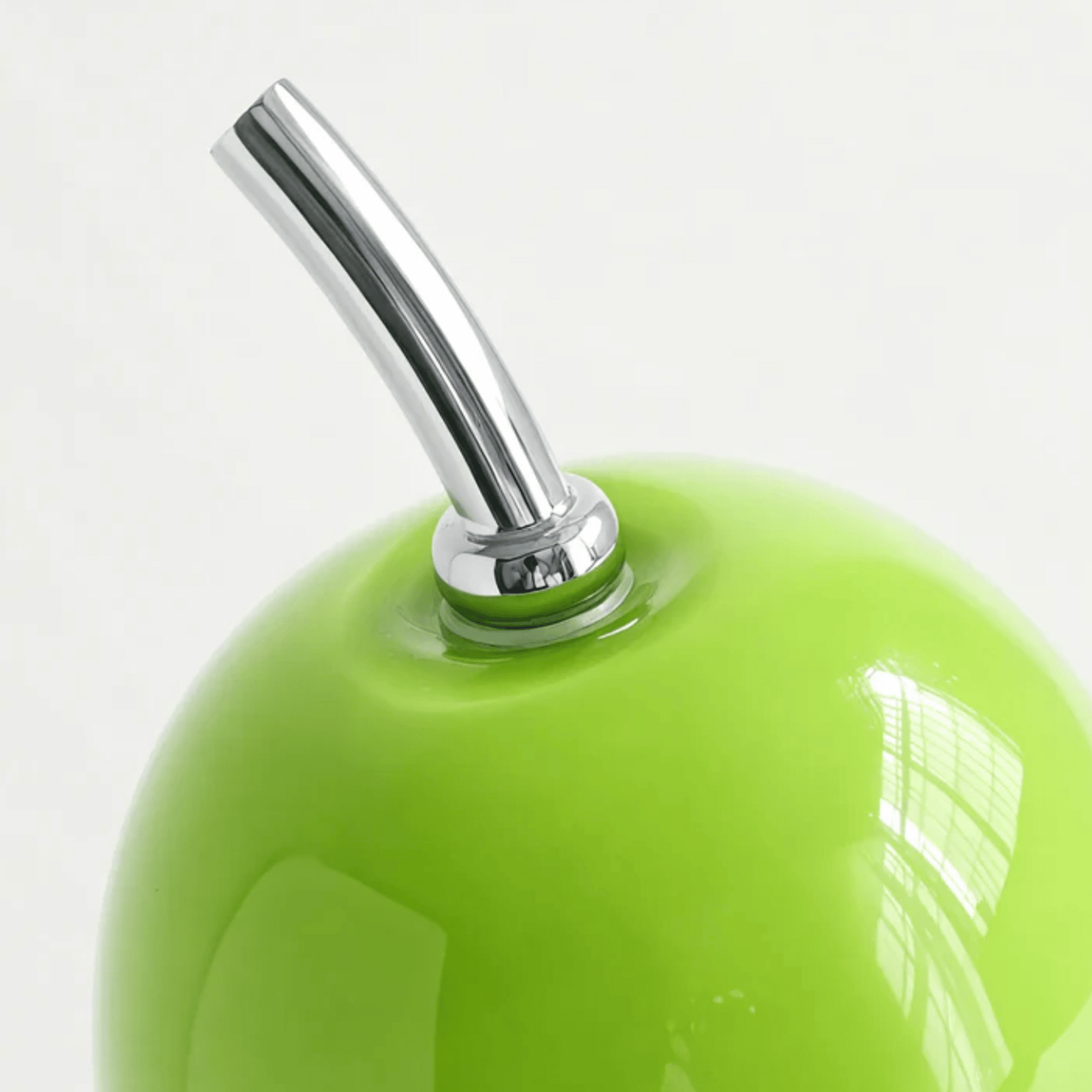 Close-up of a green apple with a silver straw on a white background