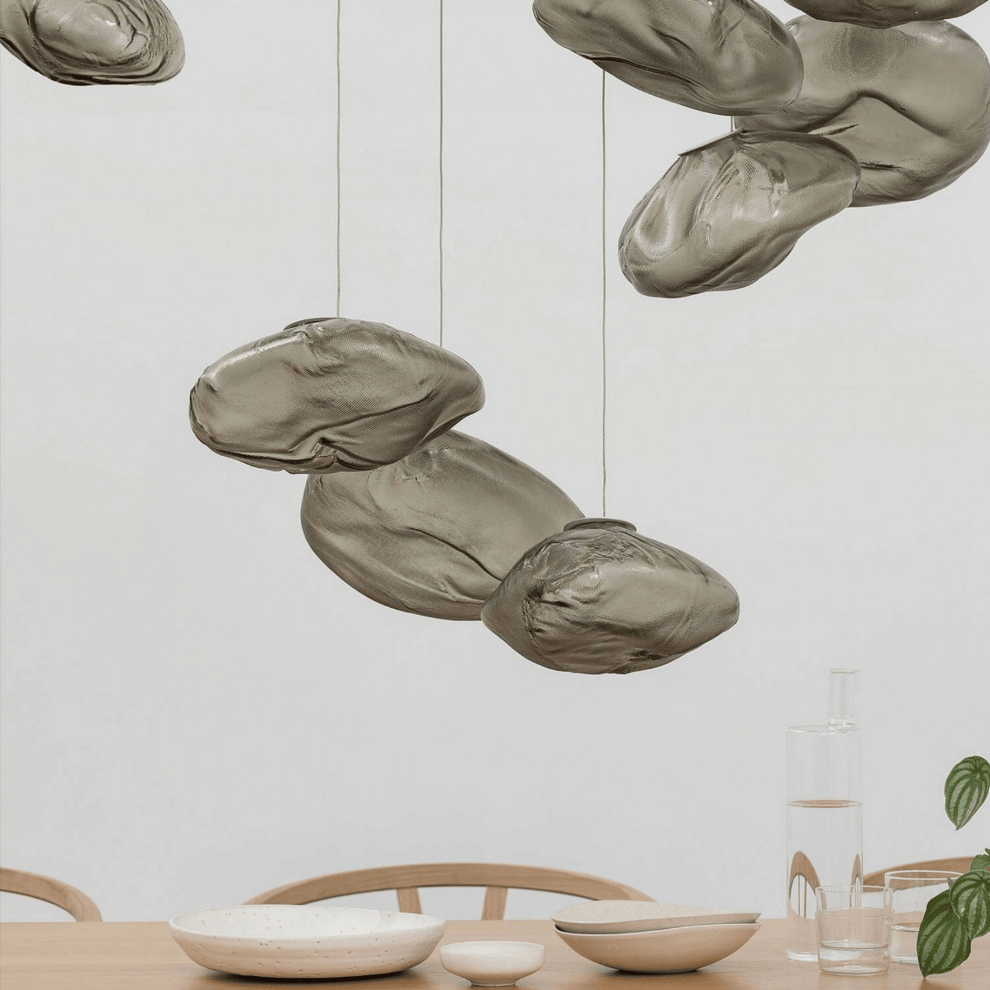 Decorative pendant lights hanging above a dining table with a neutral background