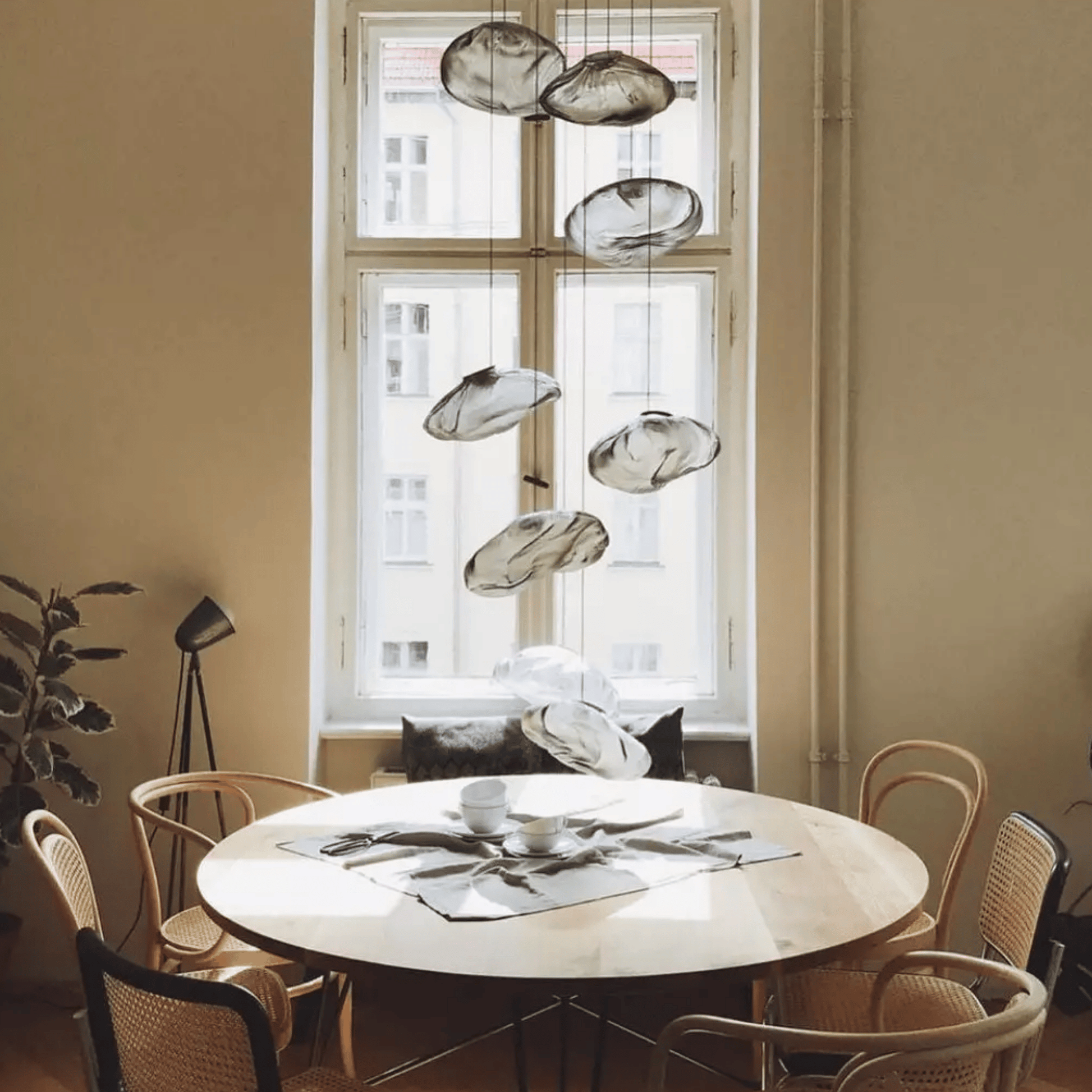 Round dining table with chairs in a room with large windows and modern pendant lights.