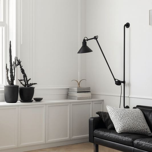 Modern living room with a black floor lamp, black sofa, and decorative plants.