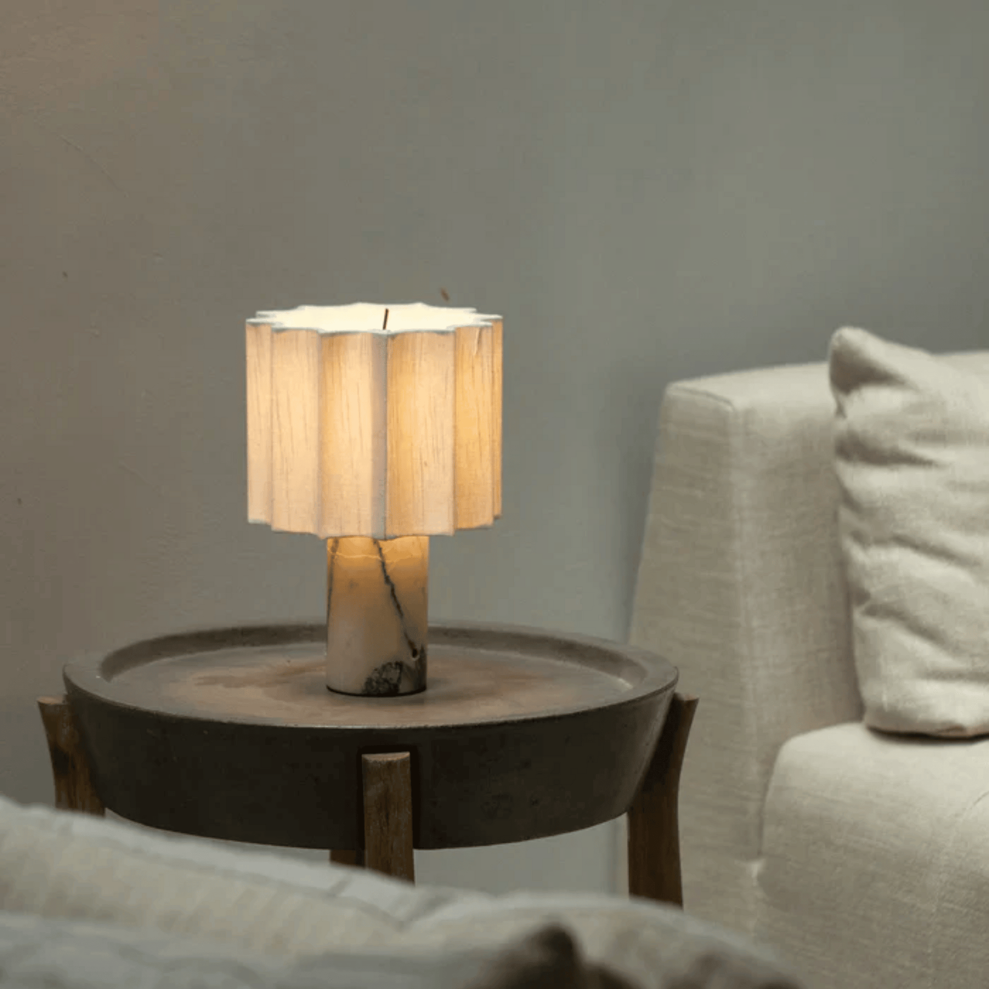 Table lamp with a wooden base on a side table next to a sofa.