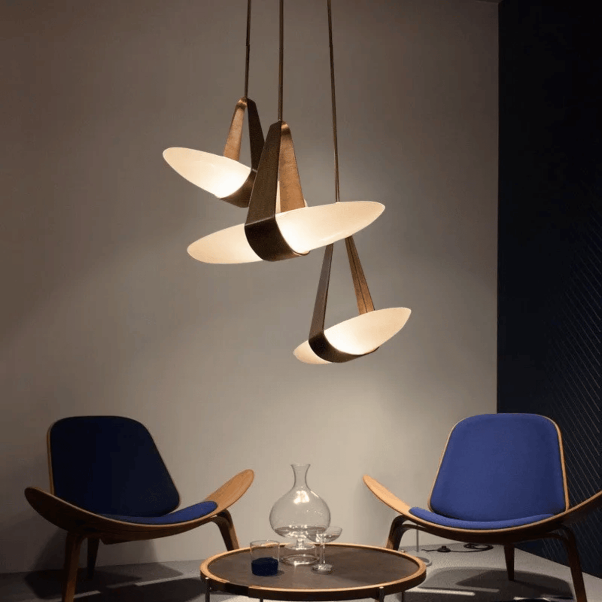 Modern pendant lights hanging above two blue chairs in a room.