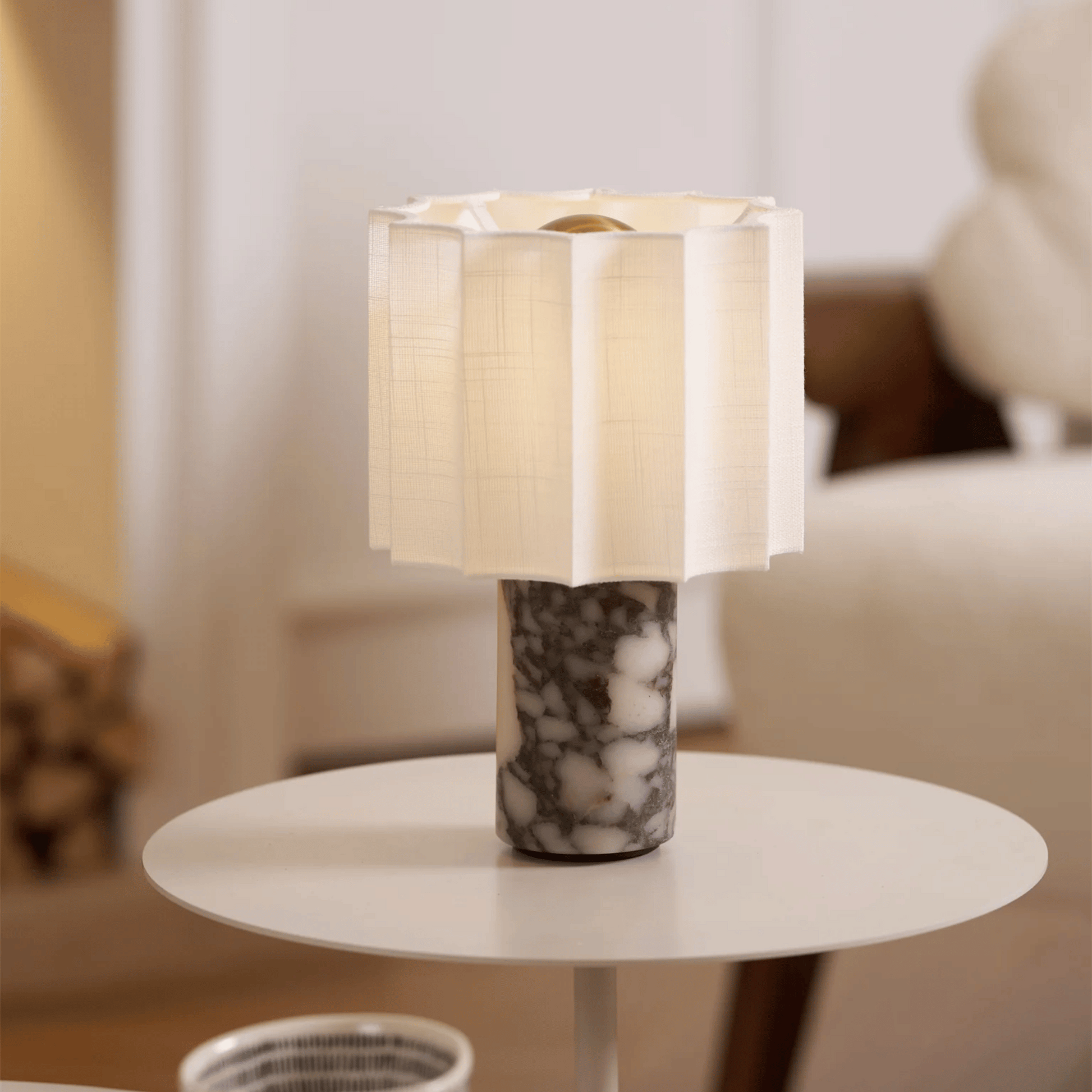 Table lamp with marble base on a round table in a blurred indoor setting
