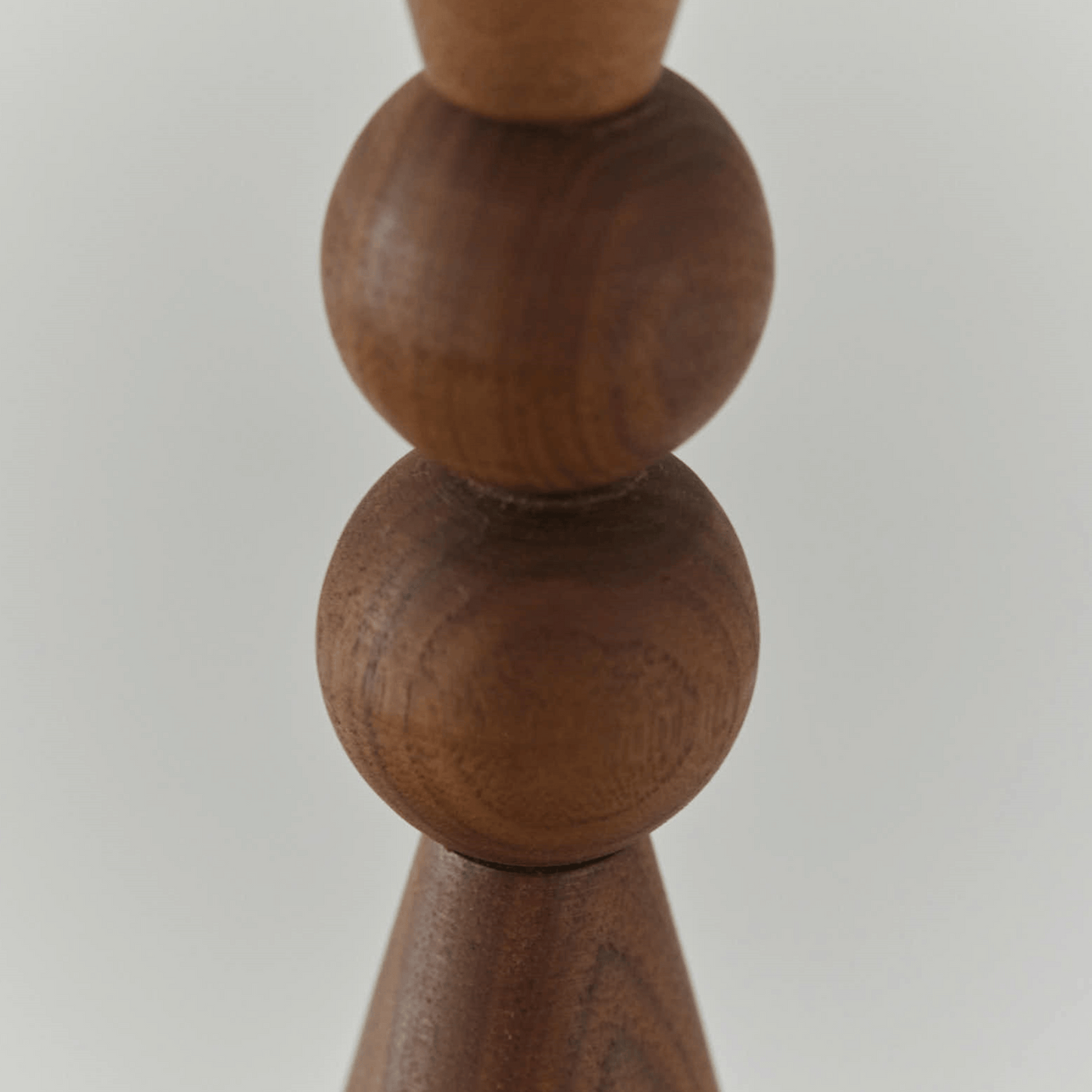 Close-up of a wooden candle holder with spherical design on a light gray background
