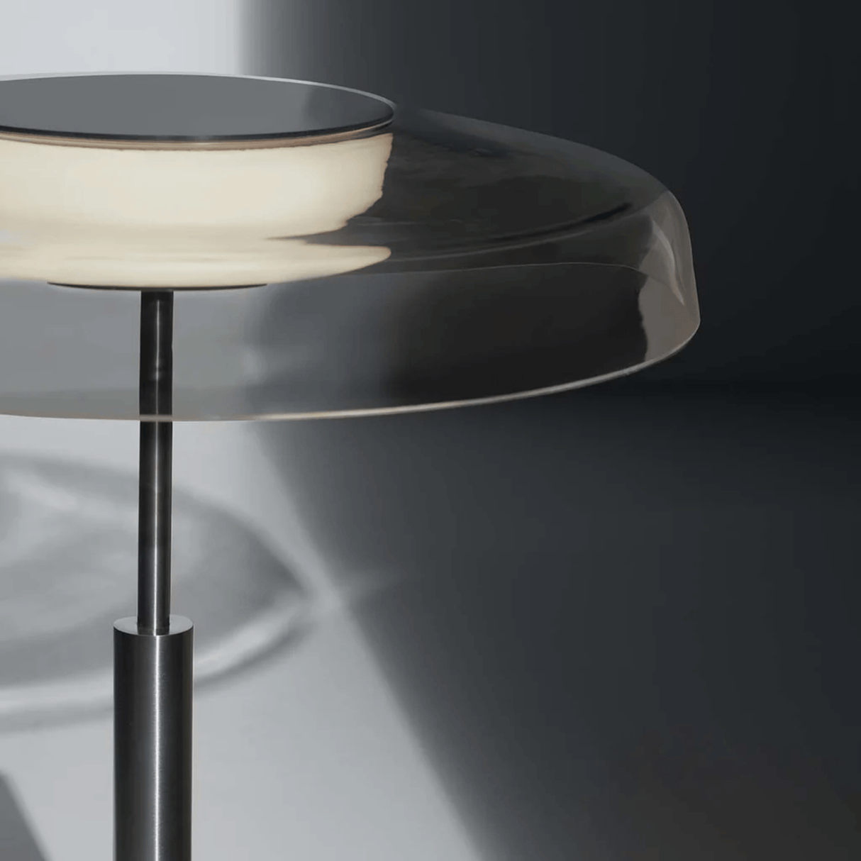 Modern side table with glass top and metal base on a dark background