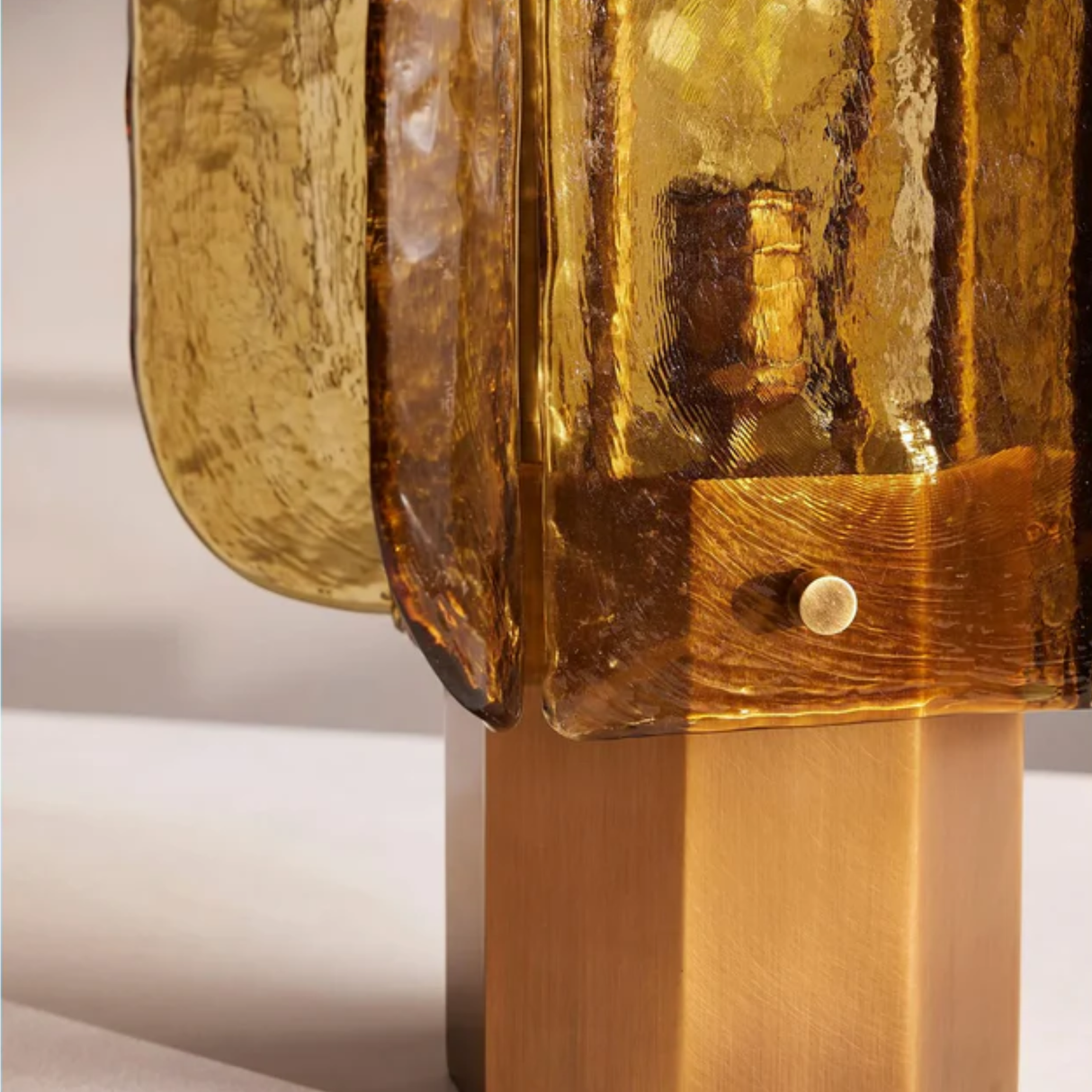 Closeup view of handcrafted amber glass lamp showing its curved glass panels and elegant warm tone