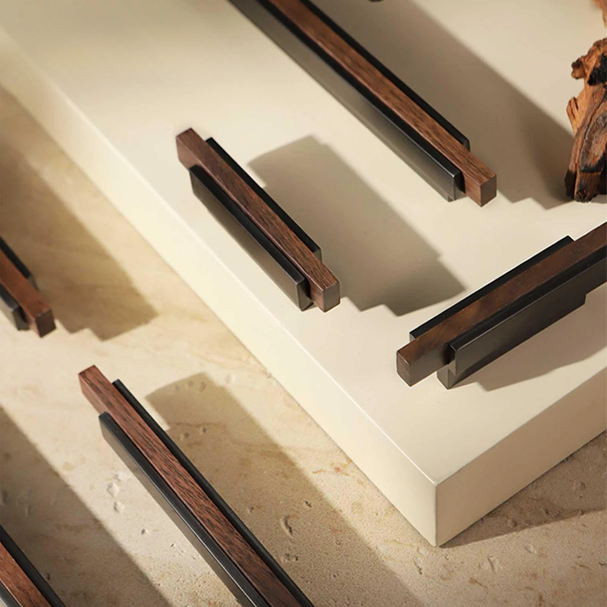Modern bronze and wood cabinet handles displayed on a light beige background with warm lighting
