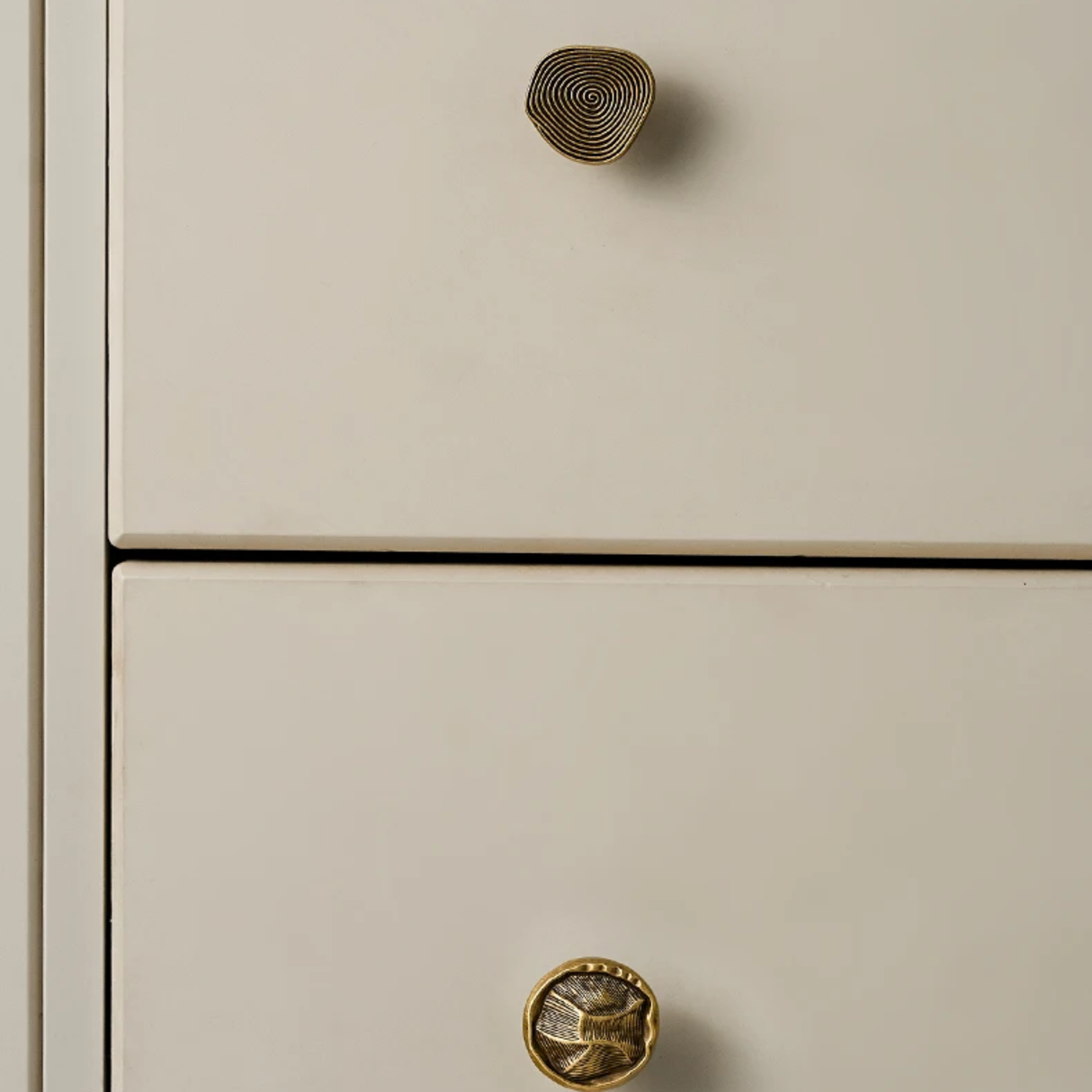 Close-up of beige cabinet doors with gold circular knobs.