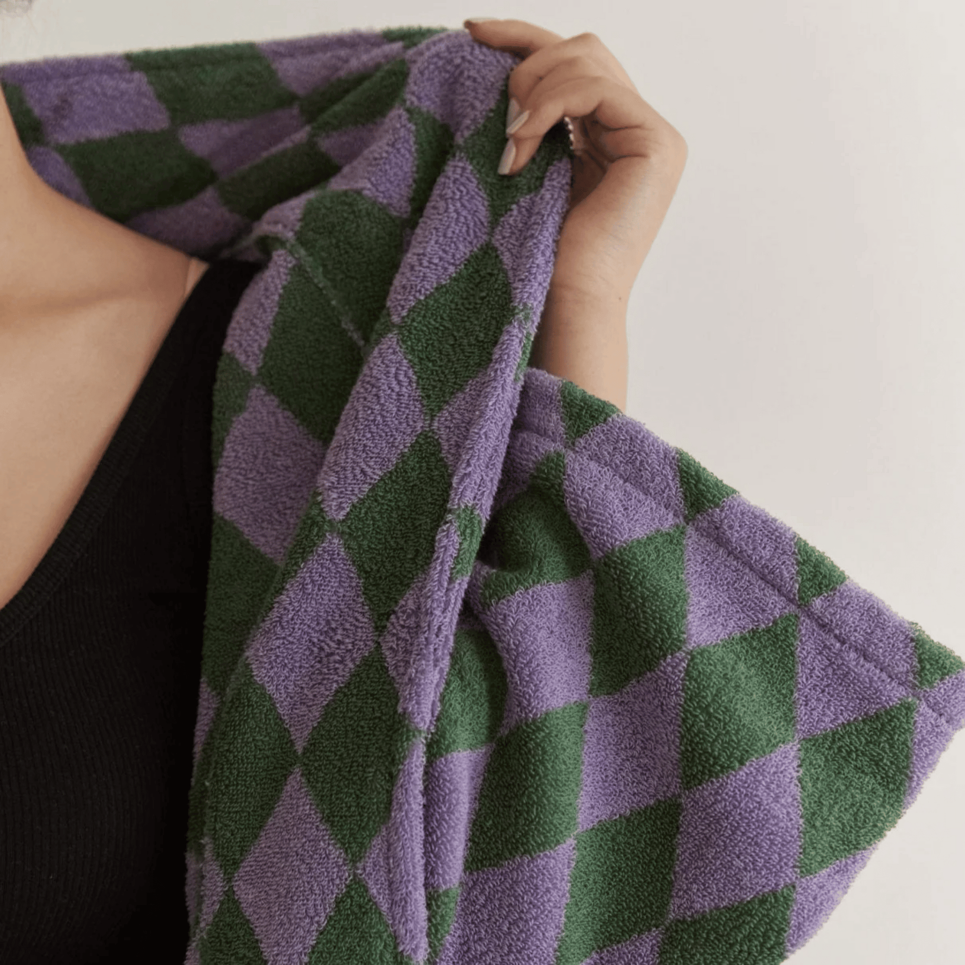 Person holding a purple and green checkered towel