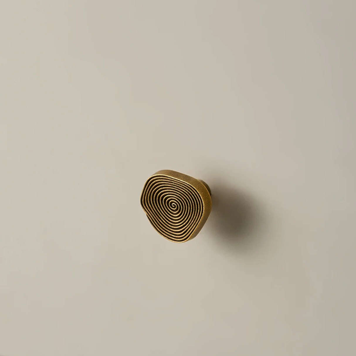 Wooden drawer knob with spiral pattern on a beige background