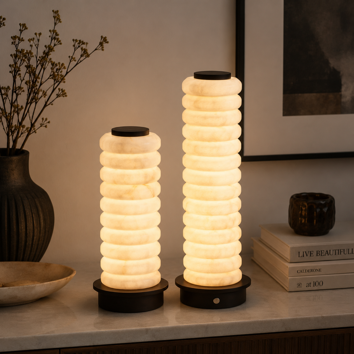 Two cylindrical table lamps with stacked ring design on a surface with decorative items.