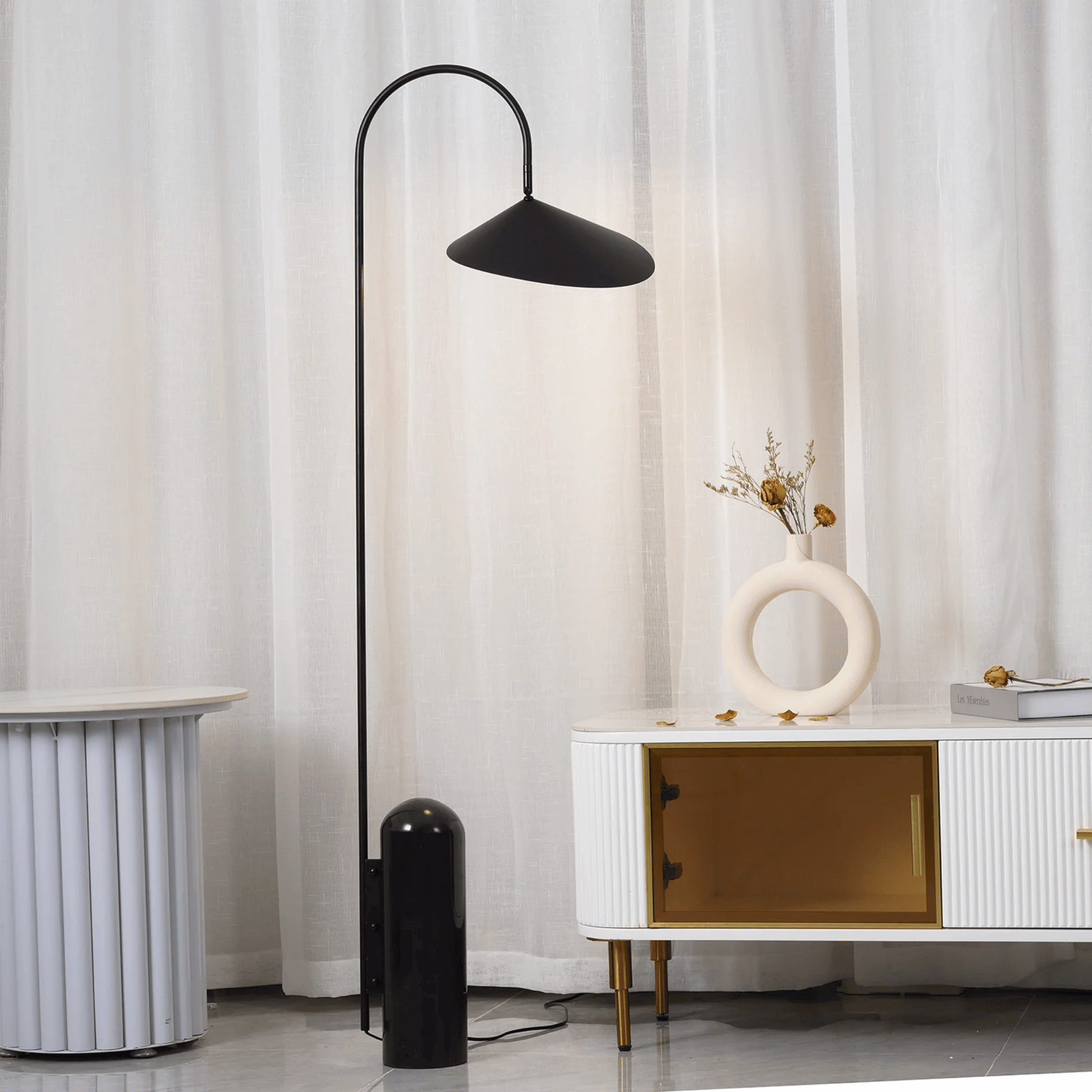 Black floor lamp in a room with white curtains and a white cabinet.