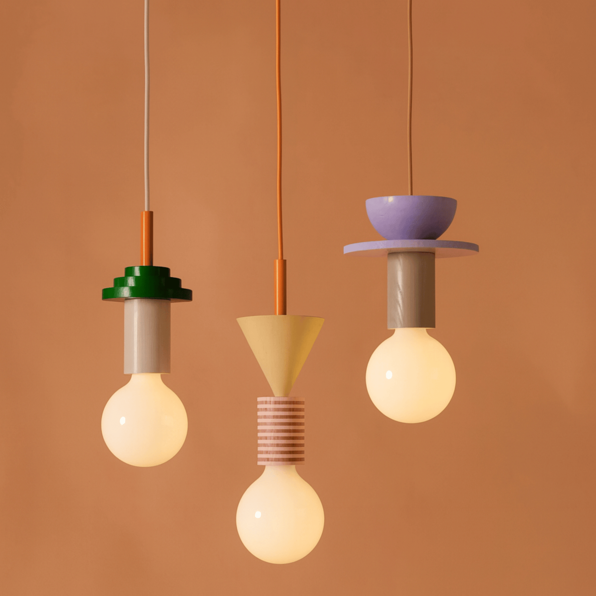 Three unique pendant lights with different designs against a brown background