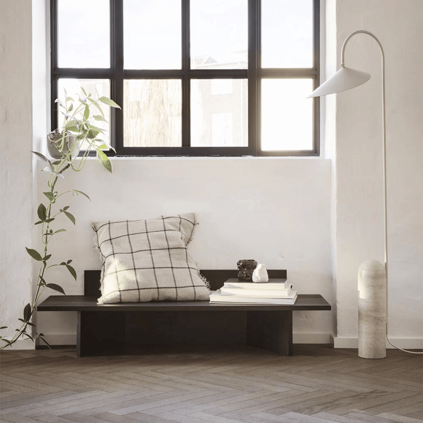 Modern interior with a bench, cushion, and decorative items near a large window.